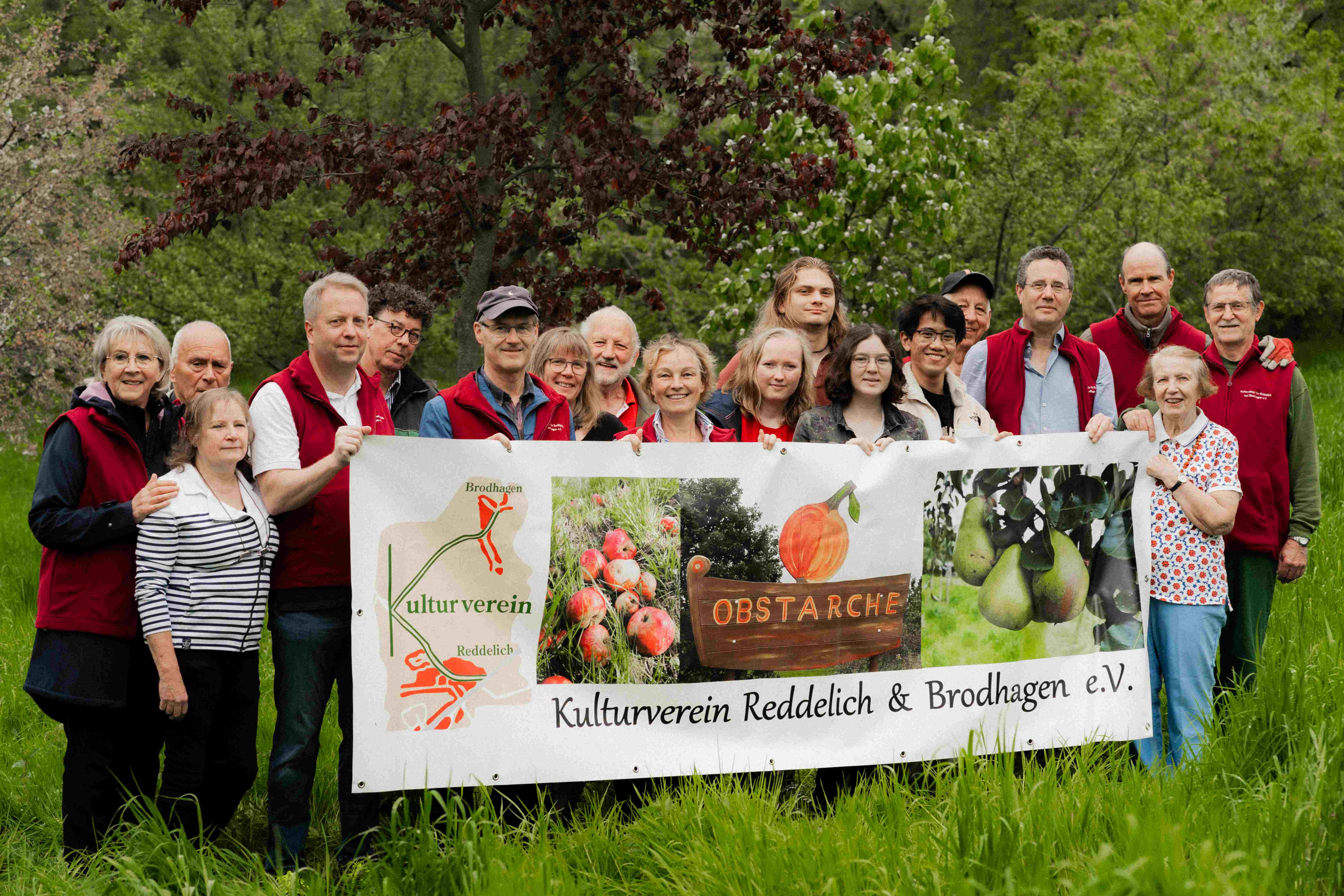Menschen der Obstarche Reddelich hinter einem Plakat
